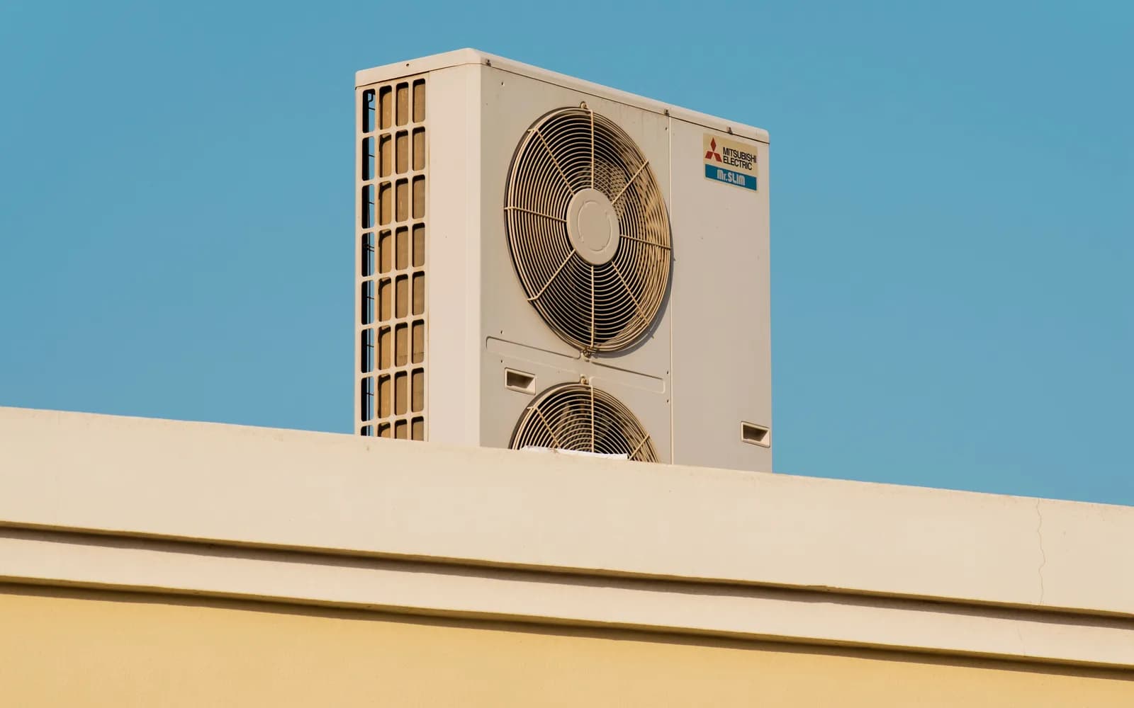 Rooftop air-conditioning condenser unit against a clear blue sky